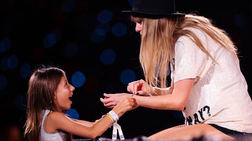 girl swapping bracelet with taylor swift during show