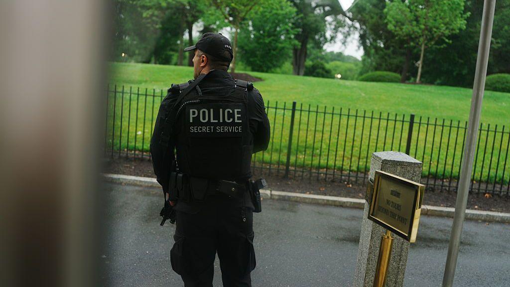 A Secret Service police officer holds his gun outside the White House press room