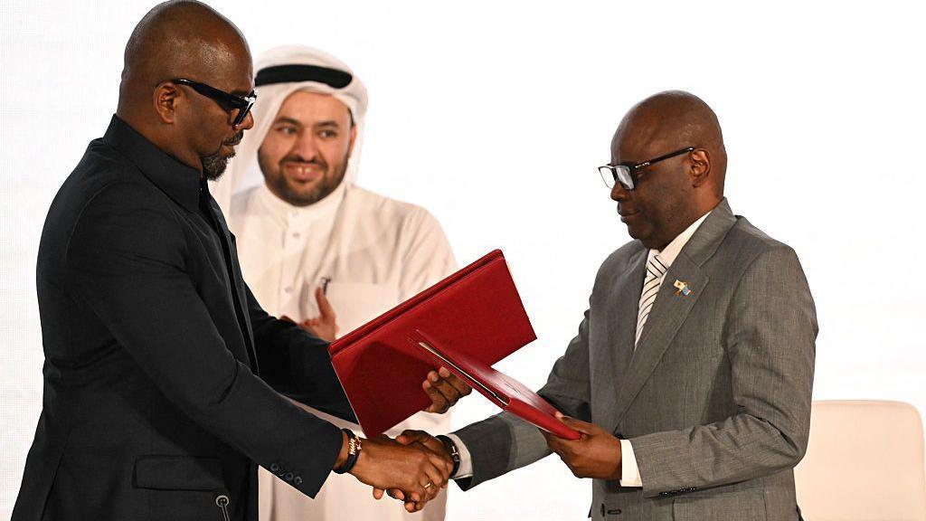 Qatar's chief negotiator Mohammed al-Khulaifi (C) observes as Sumbu Sita Mambu (L), a high representative of the head of state in the Democratic Republic of Congo (DRC) and and Rwanda-backed armed group M23 executive secretary Benjamin Mbonimpa (R) as they shake hands during the signing ceremony of the Comprehensive Peace Agreement between the DRC Government and the Congo River Alliance/March 23 Movement (AFC/M23) at the Sheraton Hotel in Doha, on 15 November.