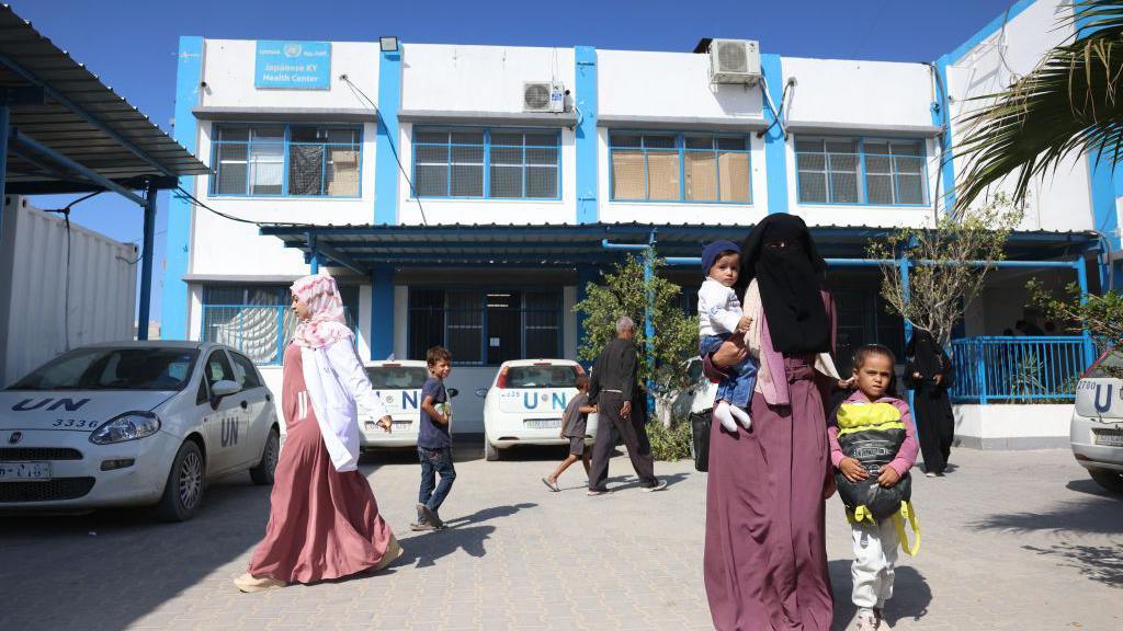 Palestinians walk outside an Unrwa medical centre in Khan Younis, in the southern Gaza Strip (29 October 2024)