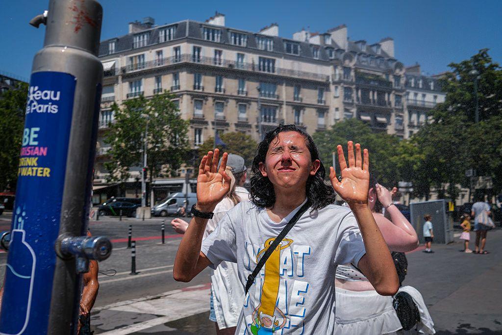A man cools down in a water spray in Paris. 