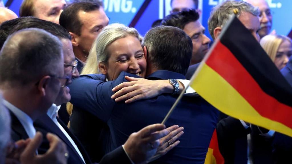 Alternative for Germany (AfD) party co-chairman Tino Chrupalla (R) and Alternative for Germany (AfD) party co-chairwoman and top candidate Alice Weidel hug and celebrate after exit polls announced.