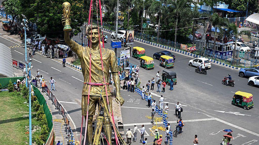 Lionel Messi's 70ft statue stands tall as workers prepare to bring it down.