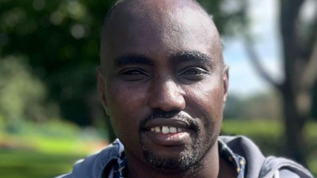 A close-up of a man in a park who is looking directly at the camera