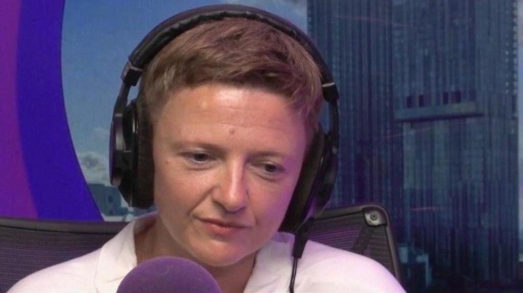Bev Craig, wearing headphones, speaks into a microphone