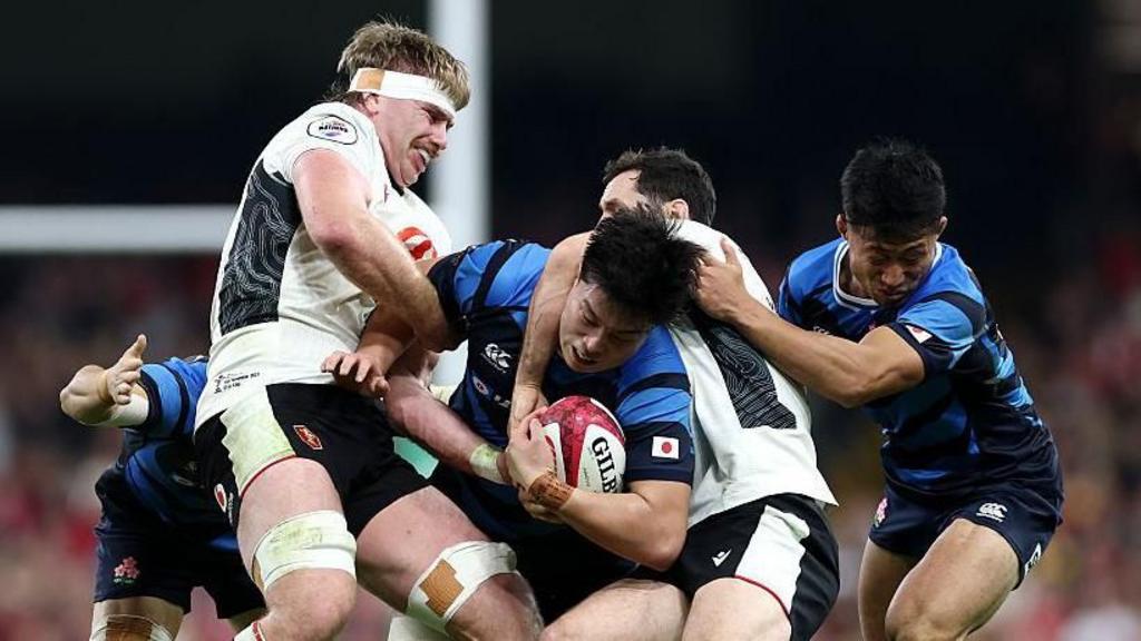 Kanji Shimokawa of Japan is tackled by Aaron Wainwright and Tomos Williams 