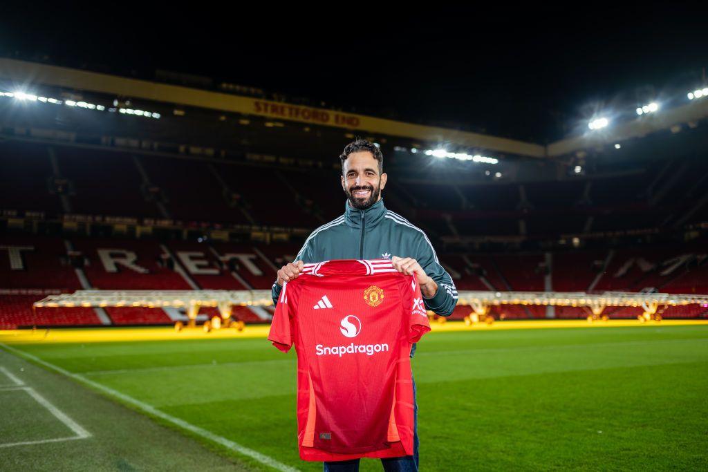 Ruben Amorim holding up a Man U shirt on a football pitch.