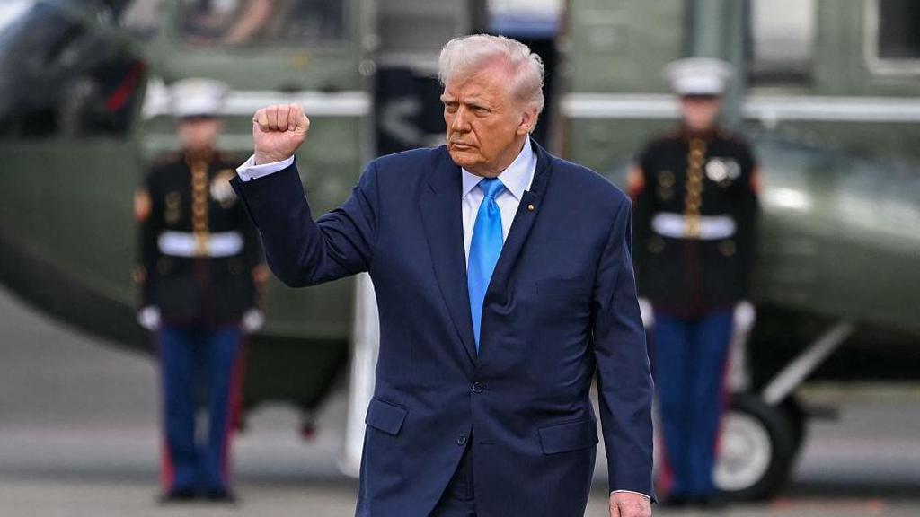 Donald trump in a blue suit walking in front of a military helicopter