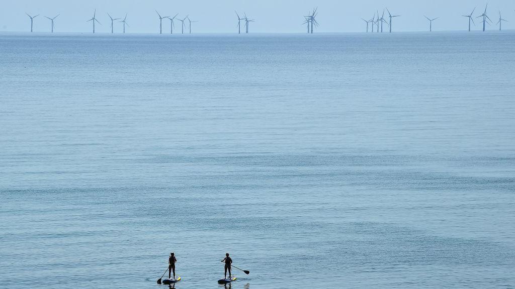 Two surfers look at the rampion farm in the sea