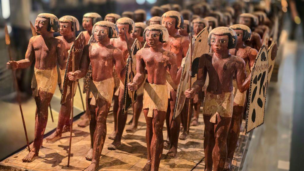 An army of statues each holding a spear and a shield, standing in lines