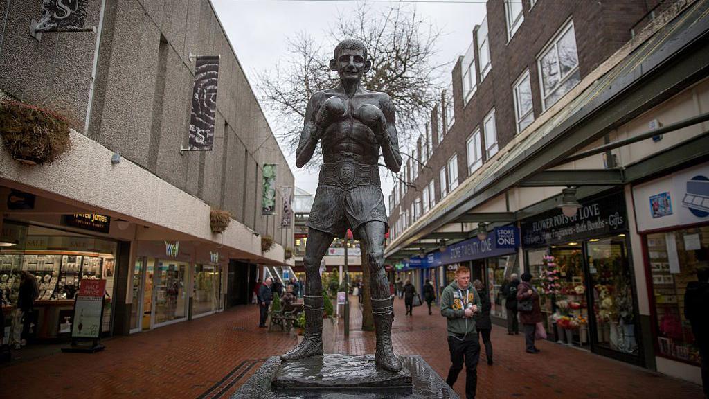 Statue of Johnny Owen in a shopping street with people walking past