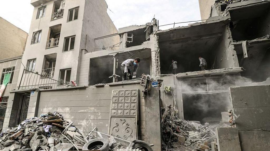 Iranian clear the debris from damaged homes in the Iranian capital Tehran on March 15, 2026. 