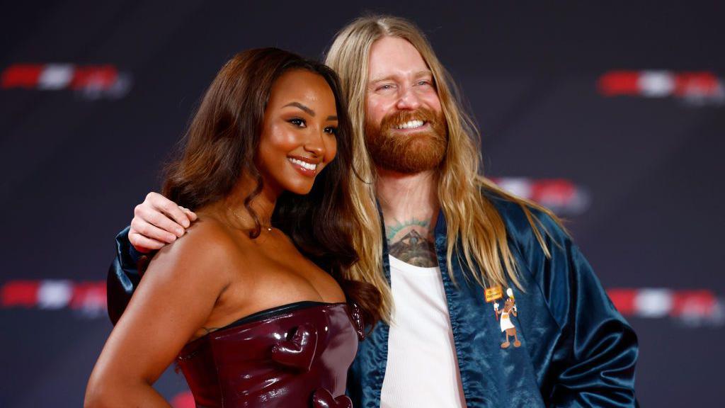 Naomi Schiff and singer Sam Ryder smile and pose for pictures on the red carpet