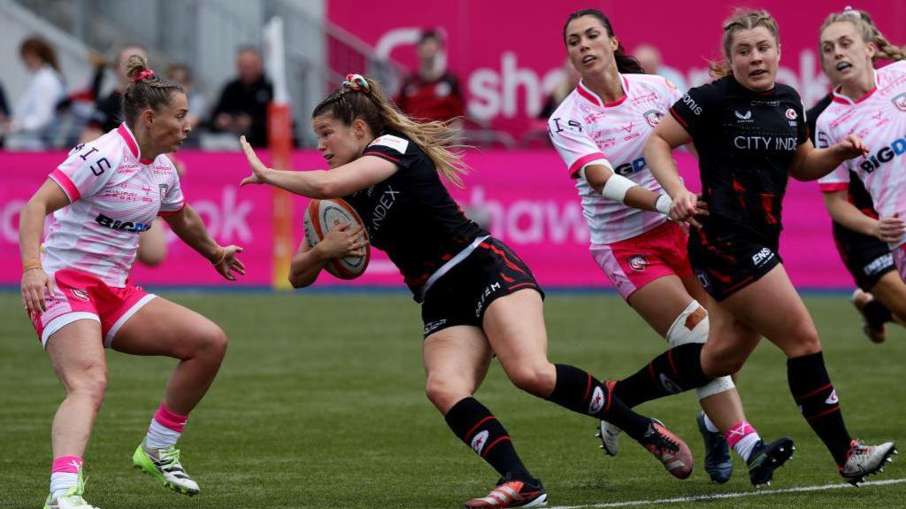 Saracens' Jess Breach runs with the ball towards Gloucester-Hartpury's Mo Hunt during their game last season 