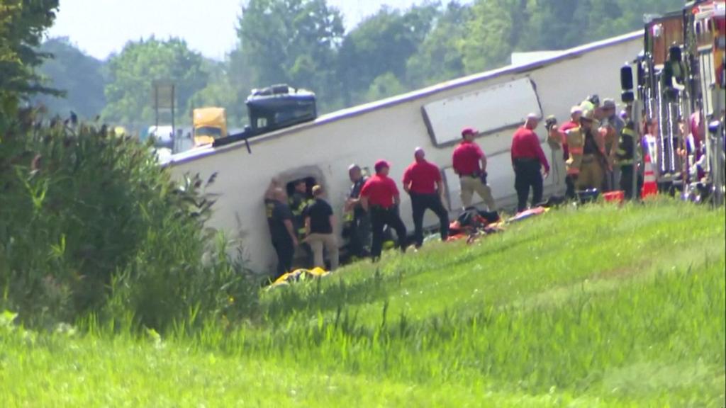 An overturned bus with emergency workers beside it