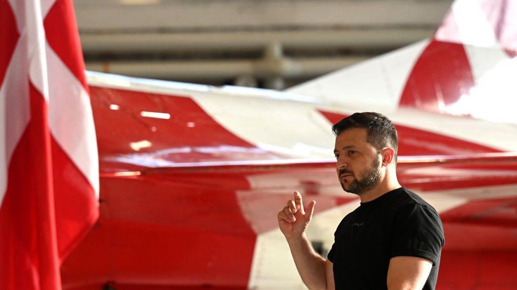 Ukrainian President Volodymyr Zelensky stands in front of a F-16 fighter jet in the hangar of the Skrydstrup Airbase in Vojens, northern Denmark