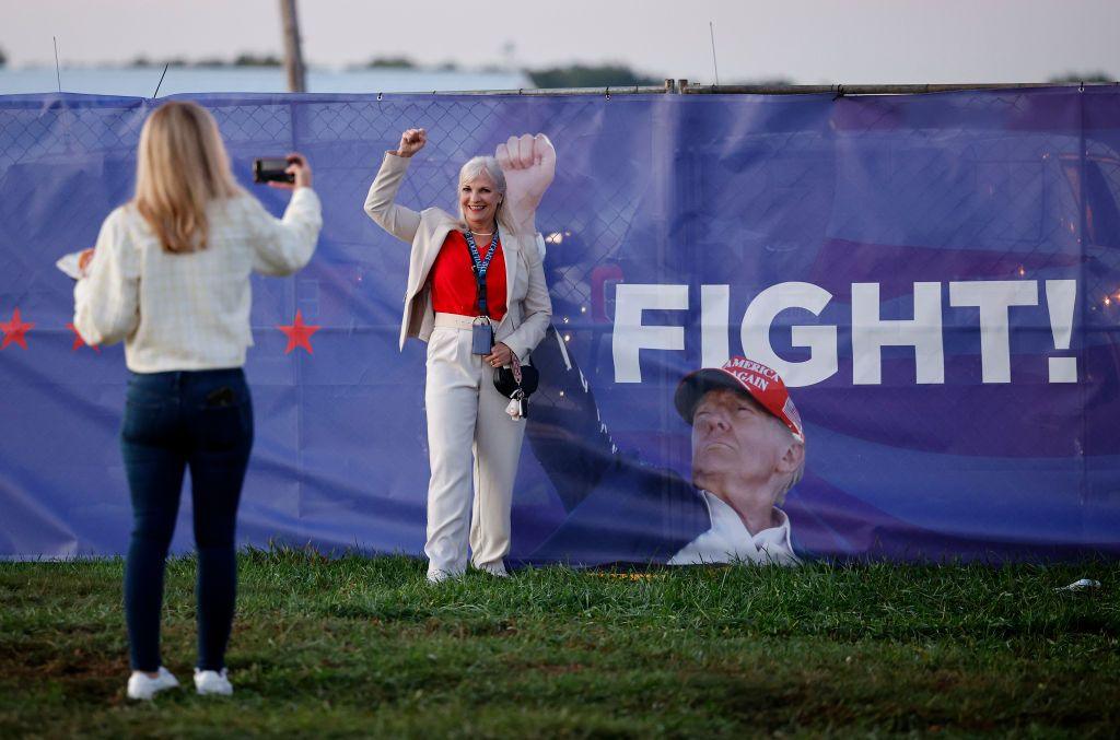 A woman takes a photo in front of a picture of Republican presidential nominee, former U.S. President Donald Trump, prior to a rally at the Butler Farm Show Inc. on October 05, 2024 in Butler, Pennsylvania