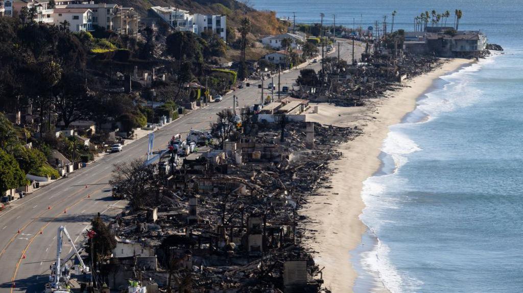 A line of burnt buildings along the sea shore