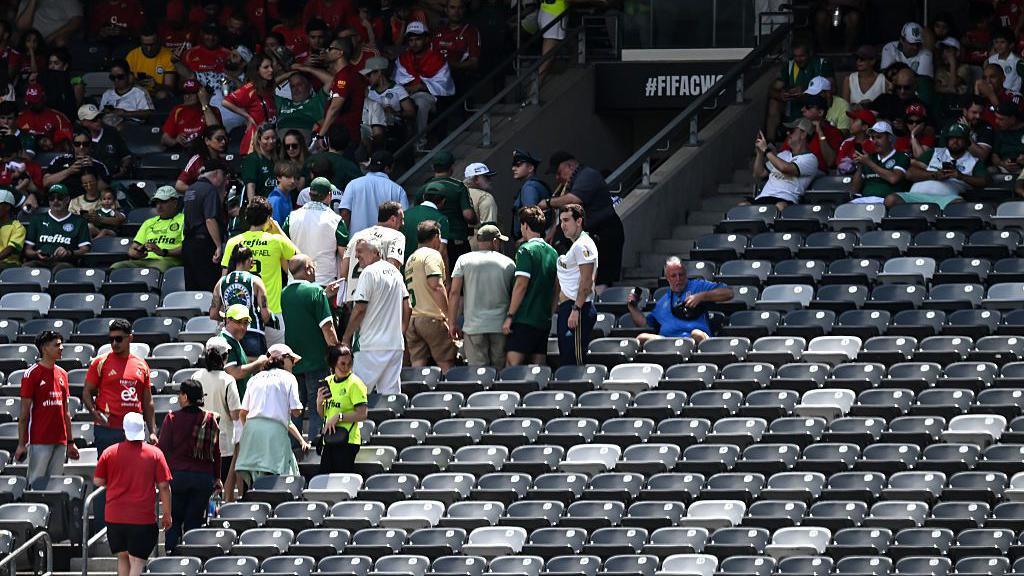 Fans leave their seats to move inside during a thunderstorm