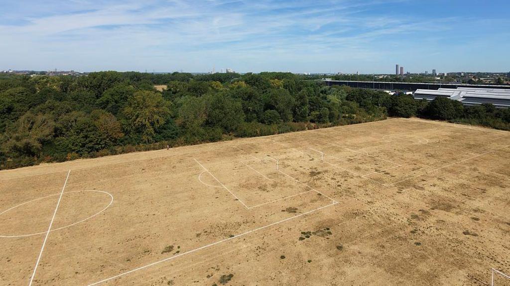 An aerial view of the dry yellow grass on a football pitch in London.