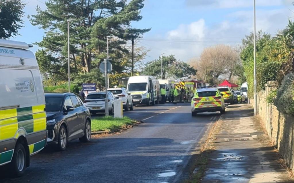 Emergency vehicles lining a street - including ambulance and police - with a welfare tent visible in the distance. Emergency workers are also pictured.