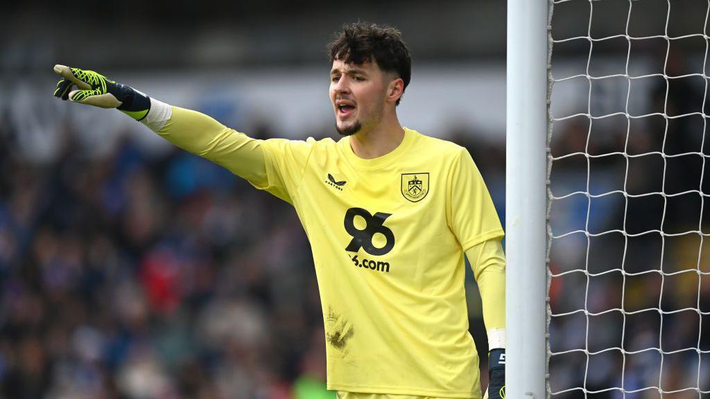 James Trafford delivers instructions to Burnley team-mates with his arm raised