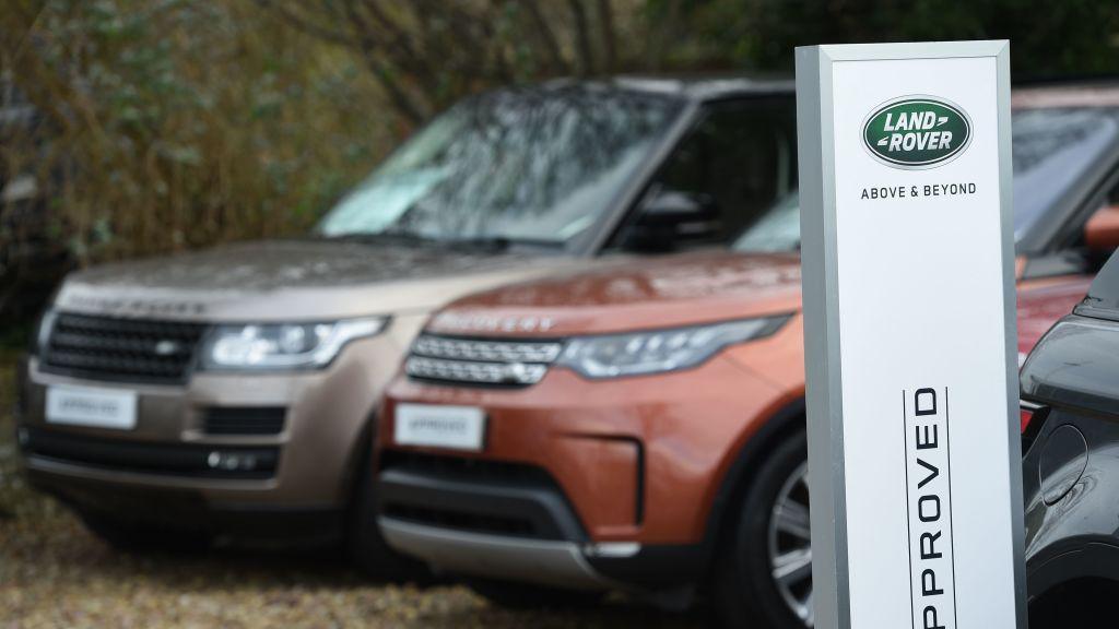 Two range rovers parked next to a sign saying Land Rover