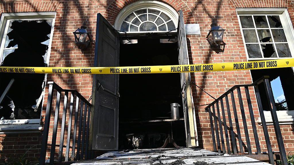 An entrance to the Pennsylvania governor's mansion is shown with police tape across it and broken windows.