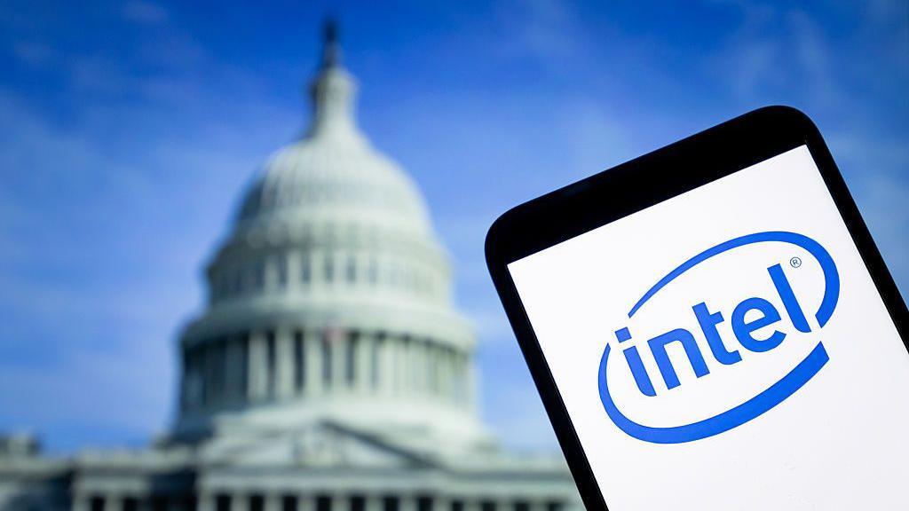 The logo of Intel is displayed on a smartphone with the US Capitol in the background.