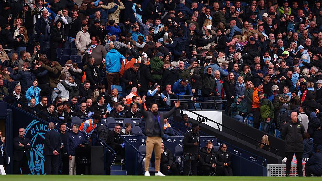 Manchester City fans do the Poznan behind Manchester United Manager Ruben Amorim