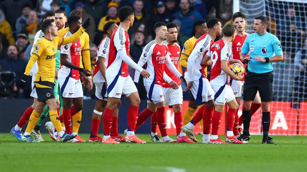 Arsenal players surround referee Michael Oliver 