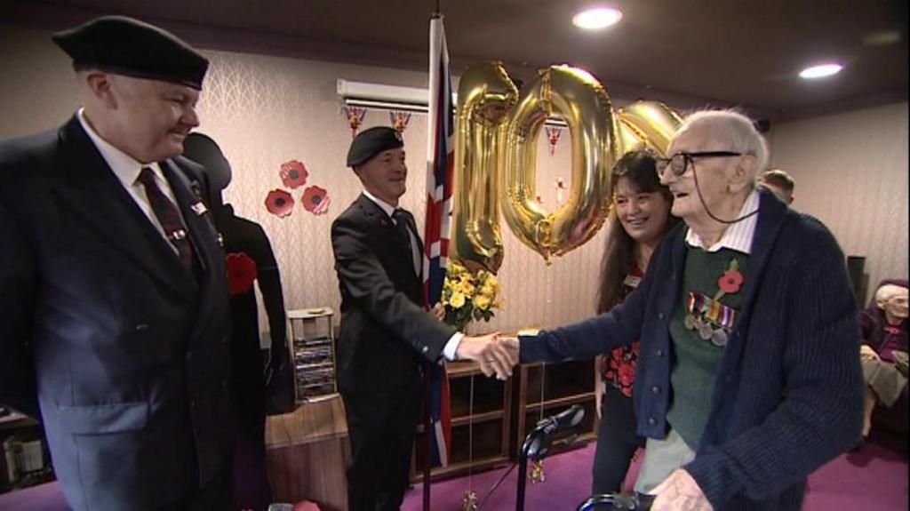 Jacke Beavon meets other veterans in front of his golden birthday balloons