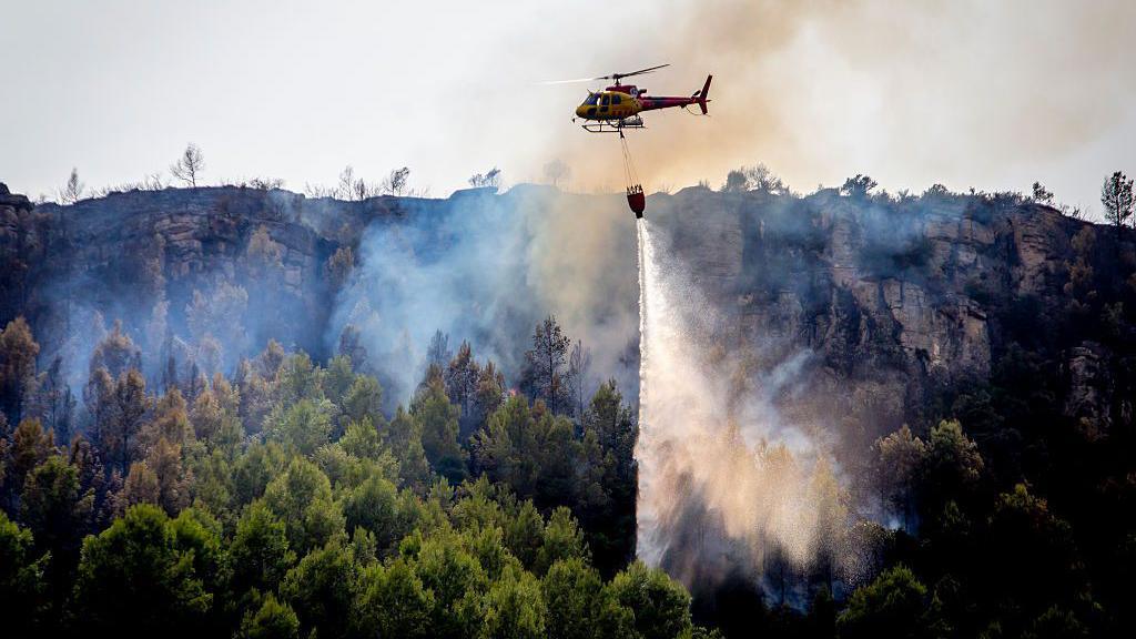 Water being poured from a helicopter onto a forest fire near Barcelona.