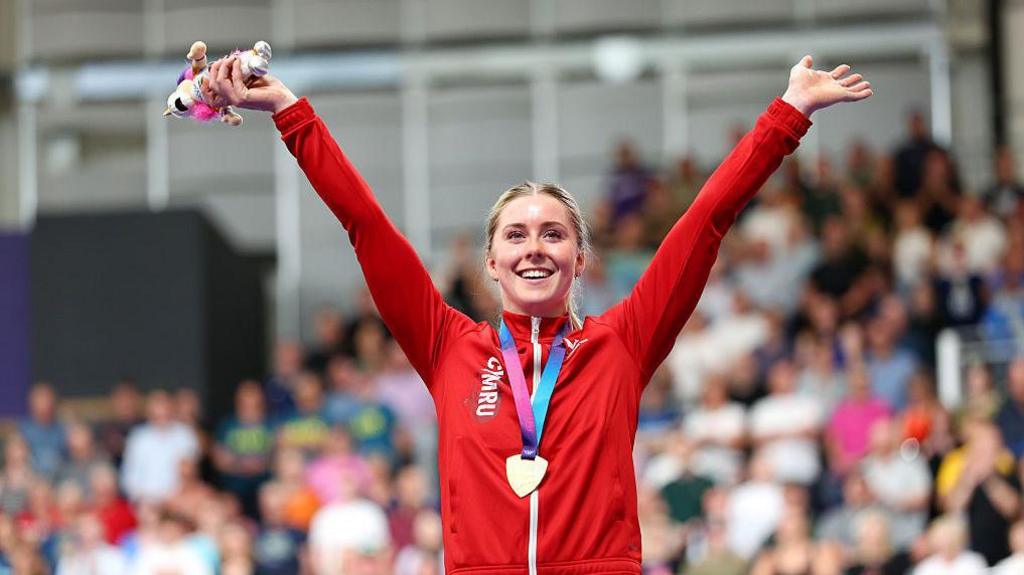 Emma Finucane arms aloft with a gold medal around her neck