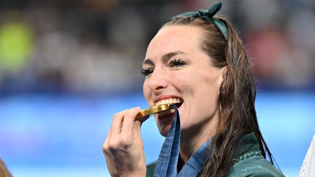 An image of South African swimmer Tatjana Smith biting into her gold medal on 29 July 2024.