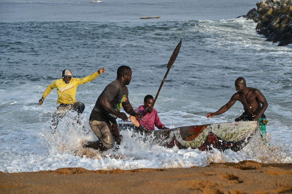 Fishermen bring their canoe in from the sea.