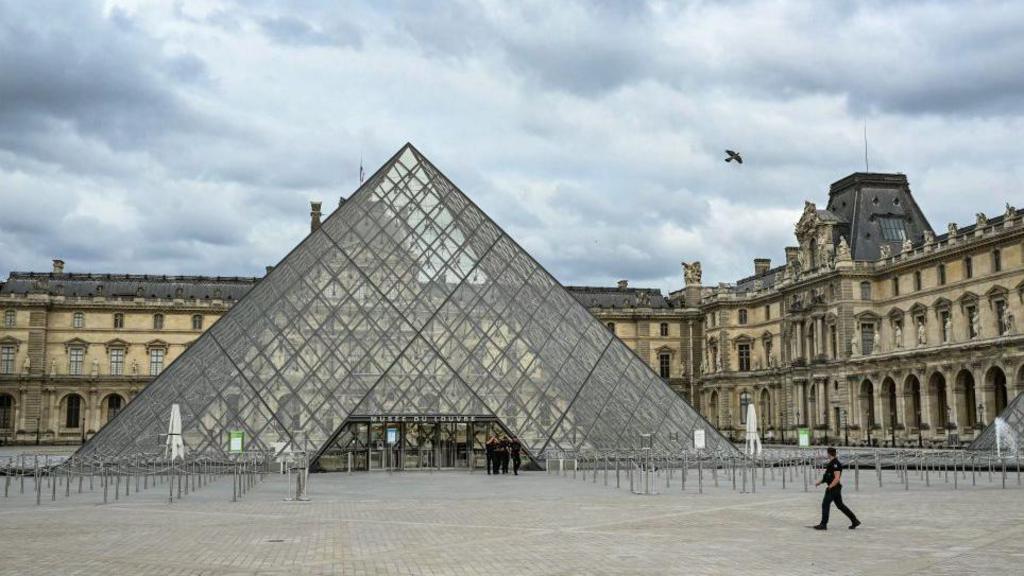 A guard walks past the Louvre