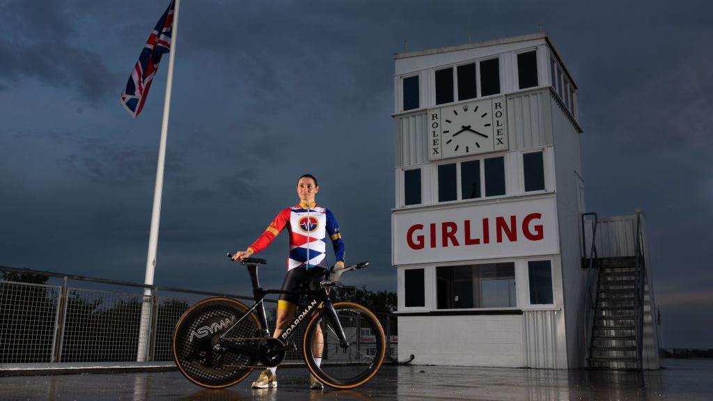 Dame Sarah Storey posing with her bike in front of a British flag