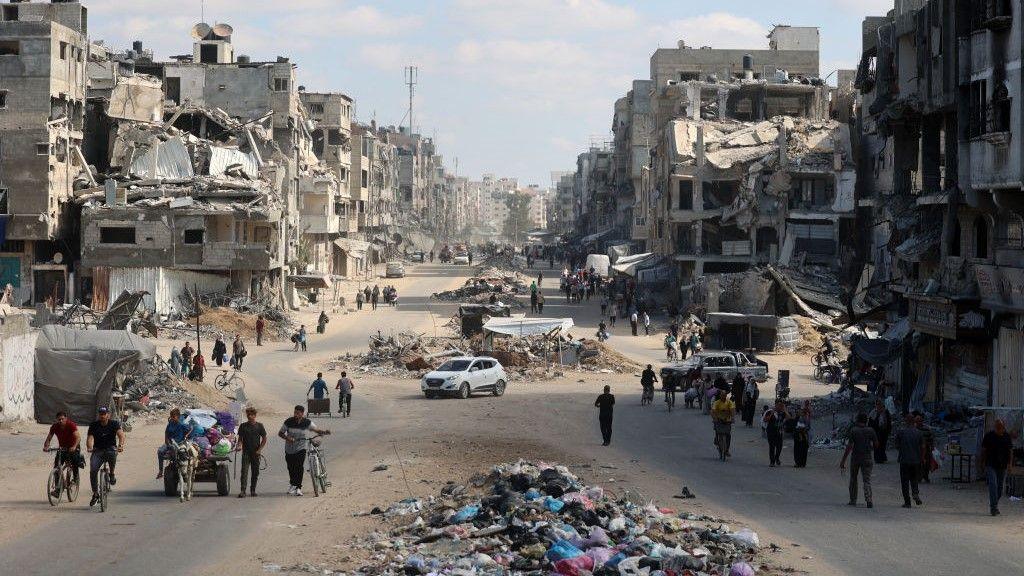 Palestinians carry their belongings as they flee areas north of Gaza City in the northern Gaza Strip, road lined with destroyed buildings