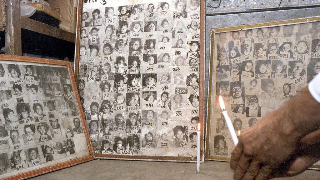 TOPSHOT - A survivor lights a candle 03 December 2002 infront of portraits of some of the thousands killed by the Union Carbide gas leak 18 years ago in Bhopal. Thousands were killed on the night of 02-03 December 1984 when cyanide gas escaped from the factory. AFP PHOTO (Photo by AFP) (Photo by -/AFP via Getty Images)