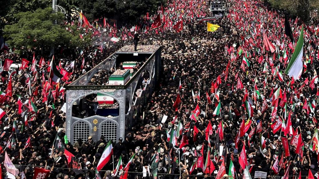 A vehicle carrying coffins of Iran's late Supreme Leader Ayatollah Ali Khamenei and his family members, makes its way through crowds of people