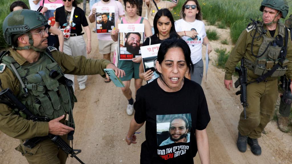 Einav Zangauker, mother of hostage Matan Zangauker, walks with a crowd behind her as soldiers walk either side of them