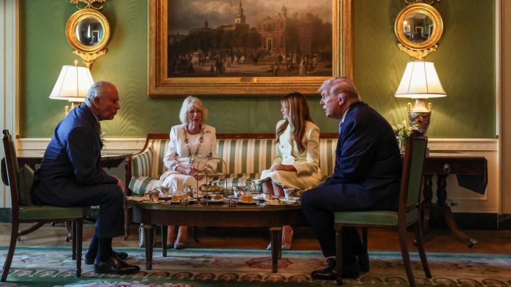 Left to right: King Charles, Queen Camilla, Melania Trump and Donald Trump sit around a low table for tea and finger food.