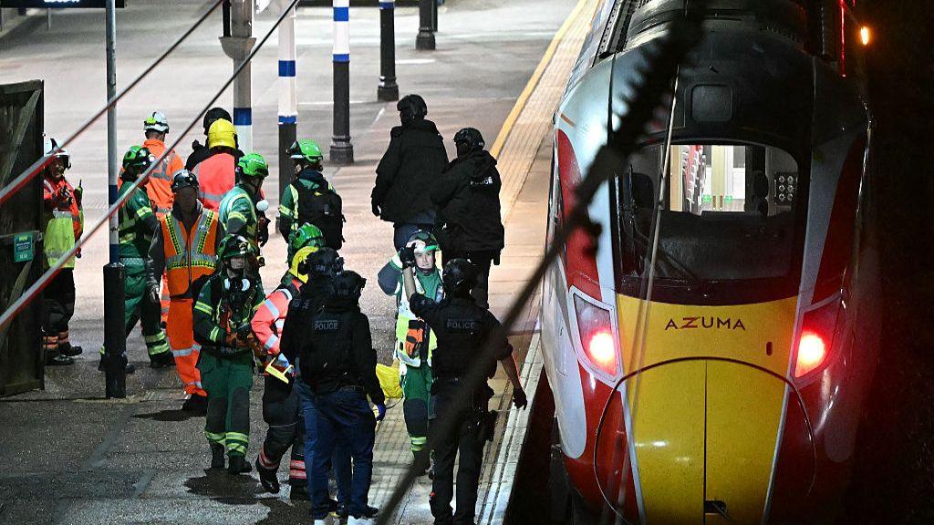Police officers and members of the Emergency services work alongside an LNER Azuma train at Huntingdon Station.