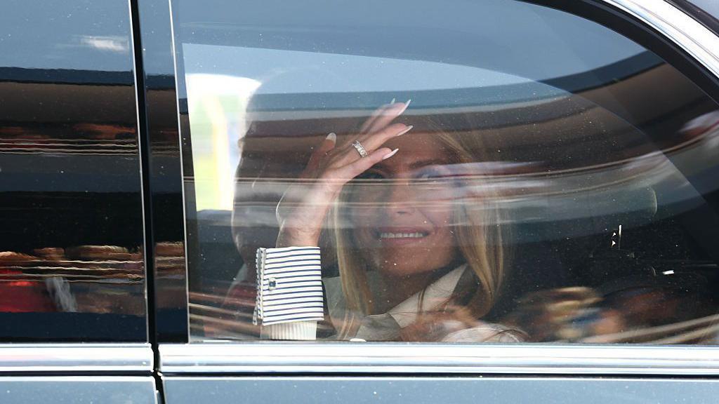 Melania Trump waves in a car