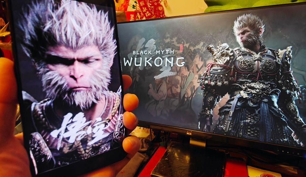 Players display a promotional poster of the Chinese and English version of Black Myth: Wukong on their mobile phones and computers 