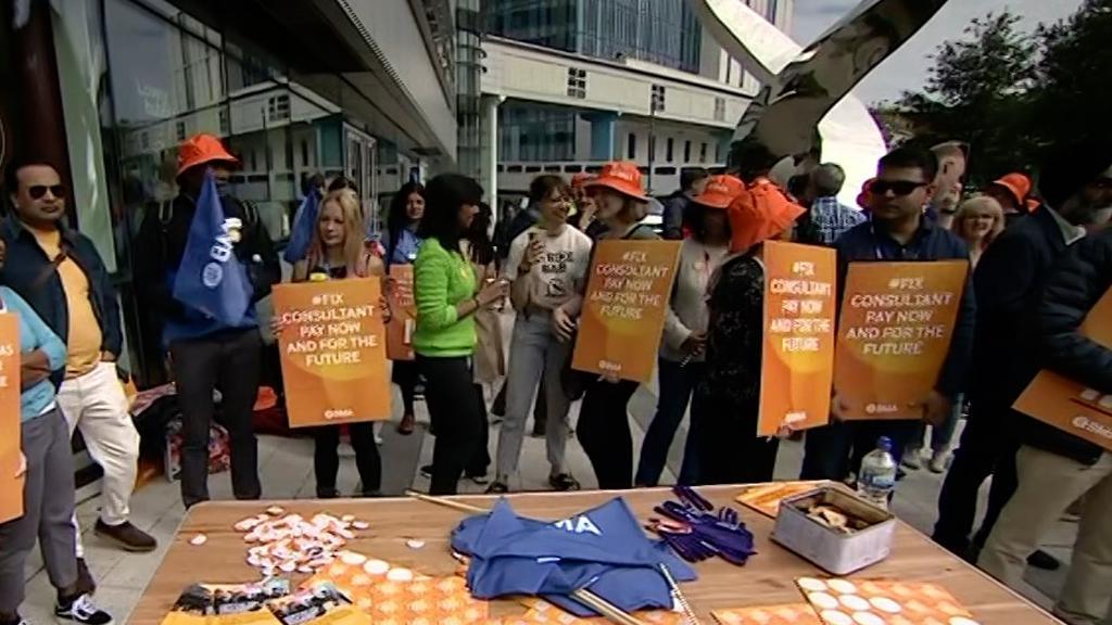 Consultants on picket line hold up banners demanding that their pay is fixed