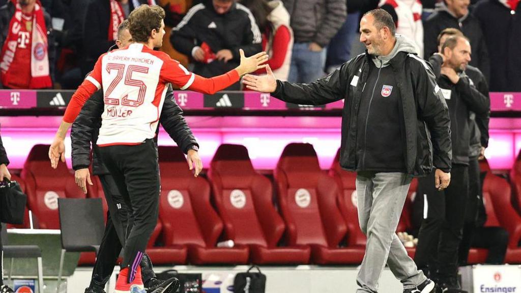 Thomas Müller of FC Bayern München (L) and Head coach Frank Schmidt of 1. FC Heidenheim 1846 high-five after the Bundesliga match between FC Bayern München and 1. FC Heidenheim 1846 at Allianz Arena on November 11, 2023 in Munich, Germany