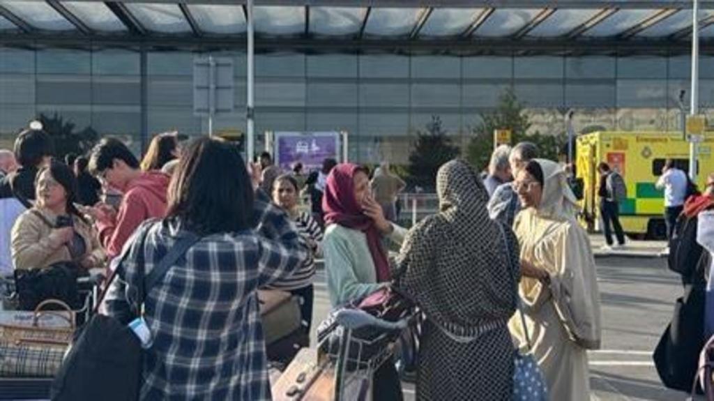 People wait outside the airport