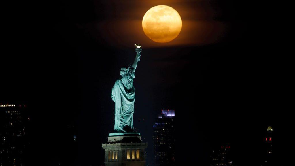 The full Worm Moon rising behind the Statue of Liberty in New York City in March 2022. 